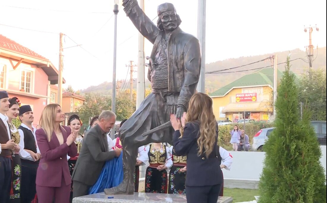 Bronzana statua Vase Čarapića sa podignutom rukom, okružena zvanicama i folklorašima u narodnim nošnjama