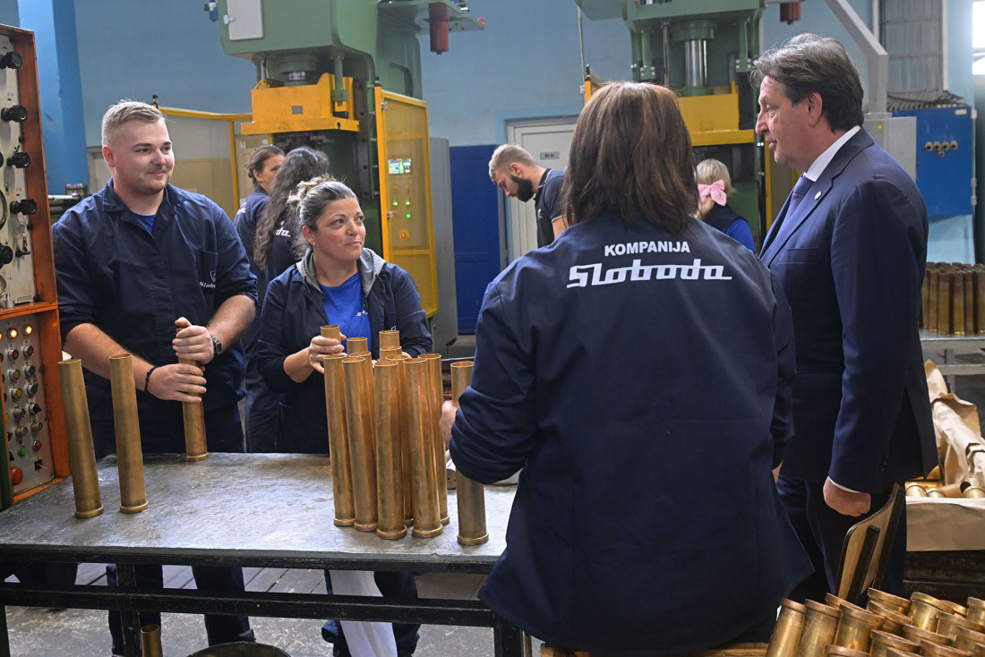 Ministar razgovara sa radnicima u pogonu fabrike, na radnom stolu su metalne čaure