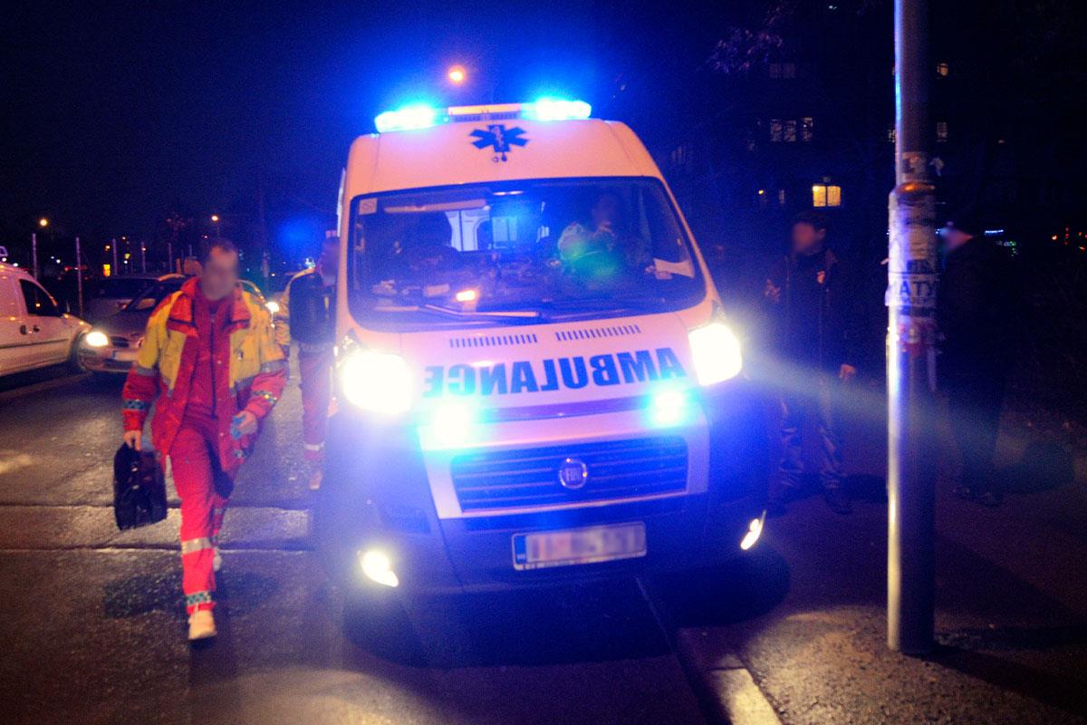 Vozilo Hitne pomoći sa upaljenim rotacionim svetlima noću i lekar sa torbom