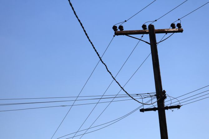 Drveni stub sa električnim vodovima na plavom nebu