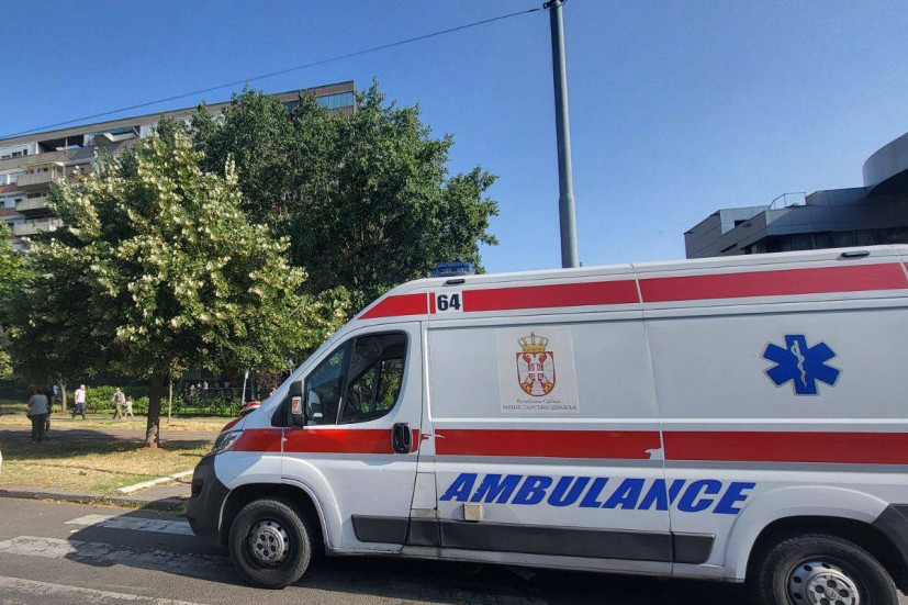 Vozilo Hitne pomoći parkirano na ulici, u pozadini drveće i zgrade