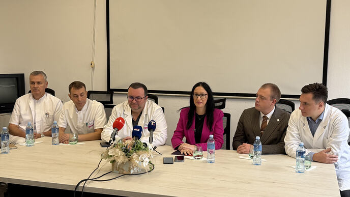 Ministarka i lekari za stolom sa mikrofonima tokom obraćanja u prostoriji klinike