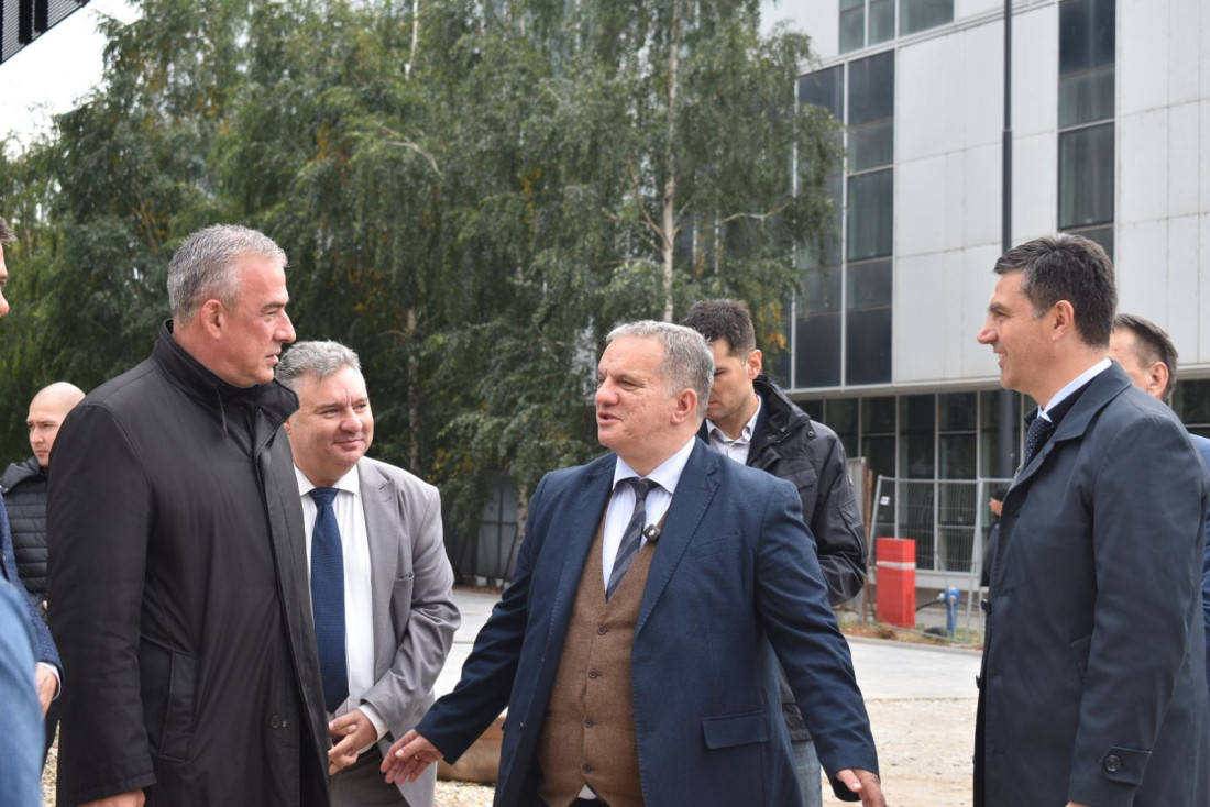 Grupa muškaraca u razgovoru ispred zgrade u izgradnji