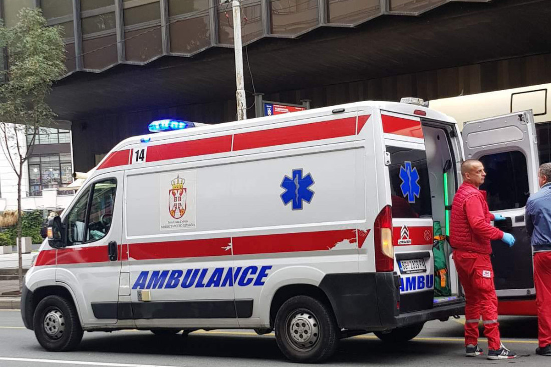 Vozilo Hitne pomoći sa upaljenim rotacionim svetlom i medicinari pored otvorenih zadnjih vrata