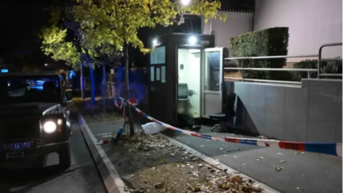Stražarska kućica ispred ambasade noću, ograđena policijskom trakom, pored službeno vozilo