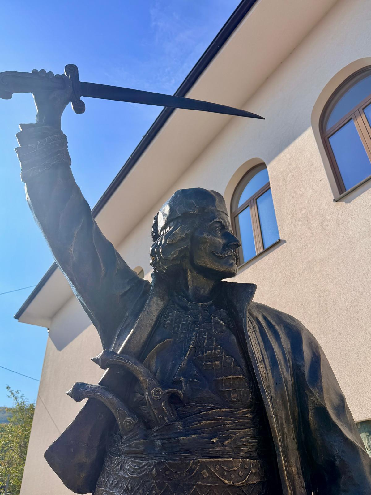 Bronzana statua Vase Čarapića sa podignutom sabljom ispred zgrade sa lučnim prozorima