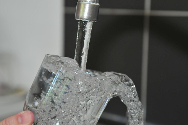 Voda teče iz slavine u staklenu posudu